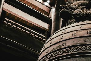 Detail of an ancient bronze bell featuring a dragon design and intricate patterns, indoors.
