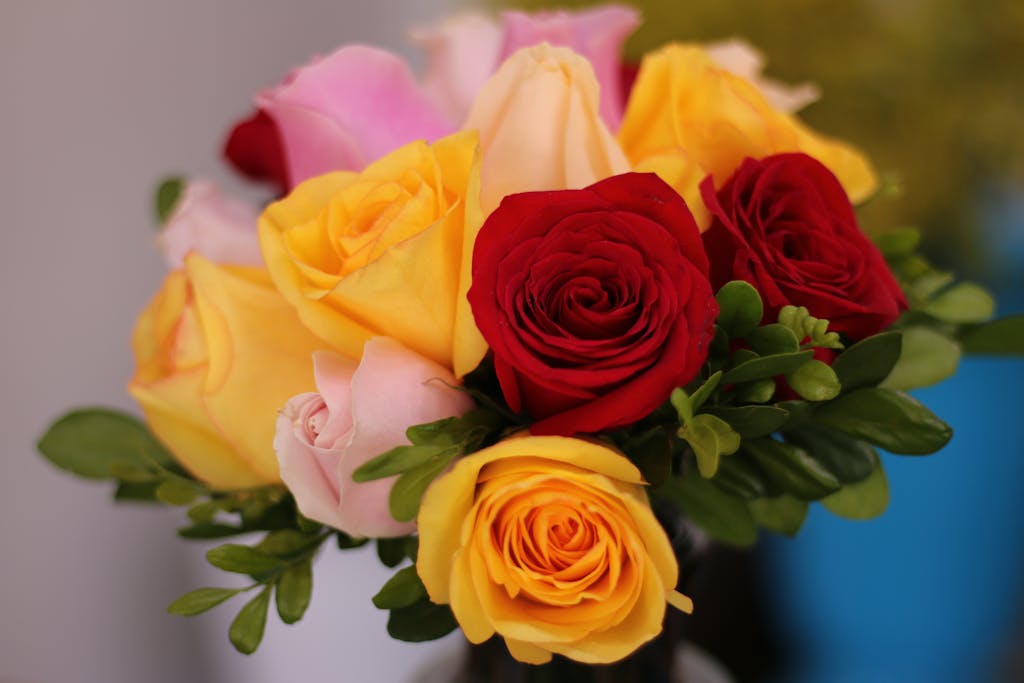 A colorful bouquet of roses with red, yellow, and pink blooms in a close-up shot.